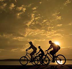 Three people cycling at sunset.