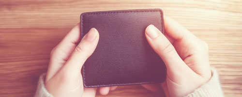 header image: A woman holding an empty black wallet, representing struggles with finances