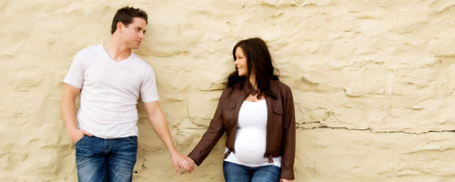 header image: A pregnant woman and a man holding hands
